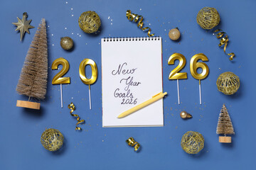 Notebook with text NEW YEAR GOALS 2026, pen and Christmas decor on blue background