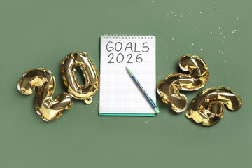 Notebook with text GOALS 2026, pen and balloons on green background