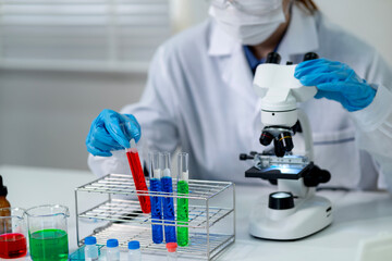 Asian adult scientist performs lab experiment holds test tube examines sample using microscope research medical discovery scientific analysis healthcare development