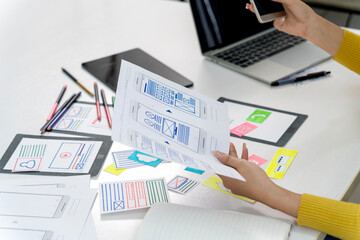 Asian adult designer hands create mobile app user interface wireframes developing new digital product experiences at modern office studio