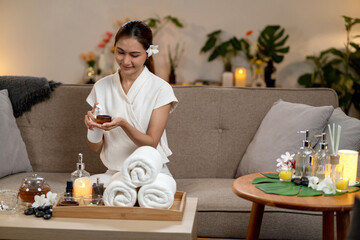 Asian adult woman enjoying home spa wellness beauty treatment pouring essential oil into wooden bowl for relaxed self care experience peaceful living room environment