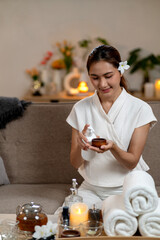 Asian adult woman prepares natural spa essential oil for calming aromatherapy massage at home creating relaxing self care moment