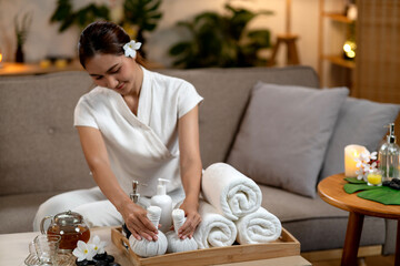 Adult Asian woman spa therapist preparing traditional herbal compress balls for relaxing massage therapy wellness treatment at home or professional spa setting