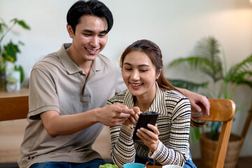 Adult Asian man woman happy share smartphone screen discuss online content connection modern home technology lifestyle