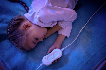 Cute little girl sleeping on electric heating pad at night, top view © Pixel-Shot