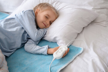 Cute little girl sleeping on electric heating pad in bedroom © Pixel-Shot