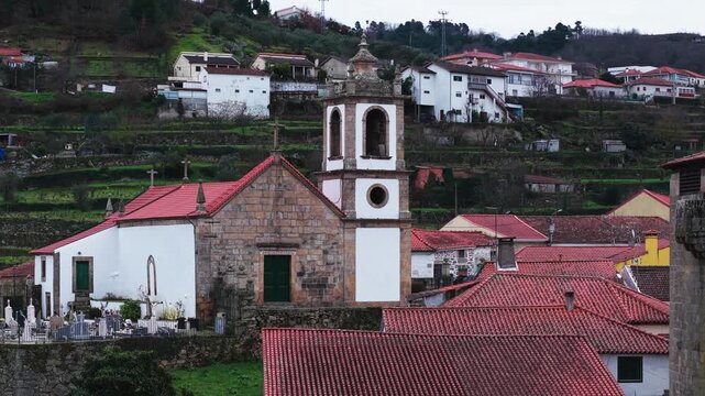 Parish Church of Ucanha with cemetery near Varosa River, Church of Saint John the Evangelist, Ucanha village traditional homes, terraced vineyards after sunset, Establishing drone shot