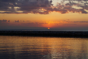 Fototapeta premium Golden dawn on the sea.The red ball of a huge sun rises from the horizon. 