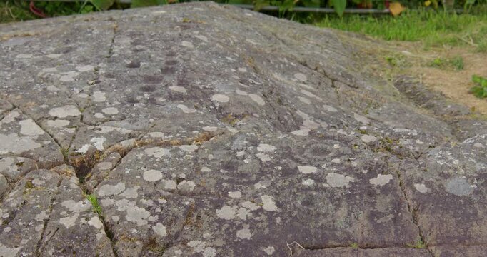 Slow zoom in of Baluachraig cup and ring carving in natural outcrop of level rock at Kilmartin glen