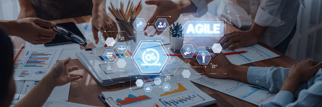Diverse professionals collaborate on a project at a wooden table, surrounded by graphs and digital agile tools reflecting a modern workspace culture. Trope - Powered by Adobe