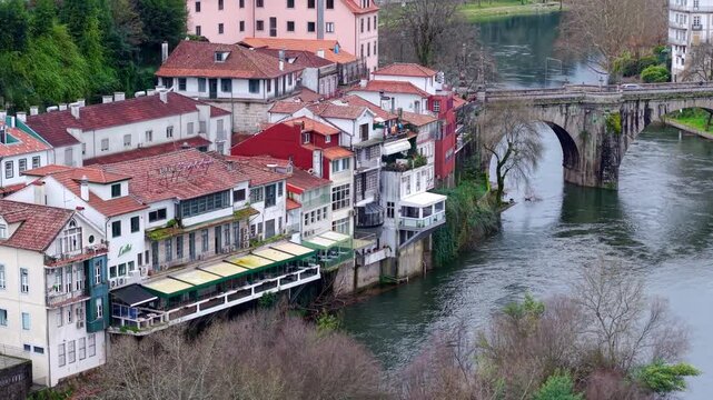 Riverside restaurants, historic Sao Goncalo bridge in Amarante city on river Tamega, Drone shot
