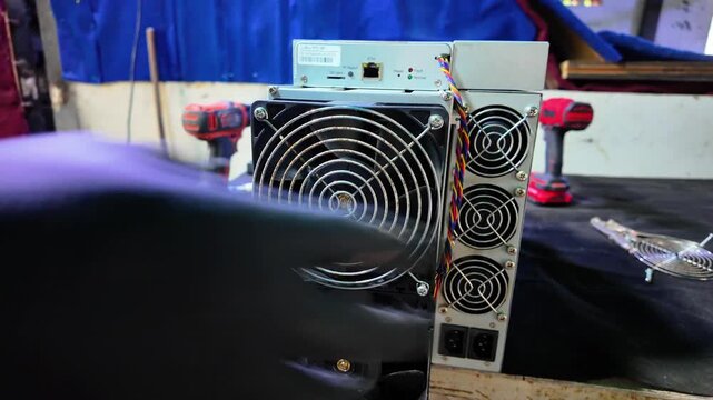 Man professional hands performs essential maintenance on cryptocurrency miner, focusing on heat management and hardware longevity