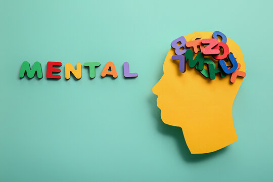 Paper human head with scrambled letters and word MENTAL on turquoise background. World Mental Health Day