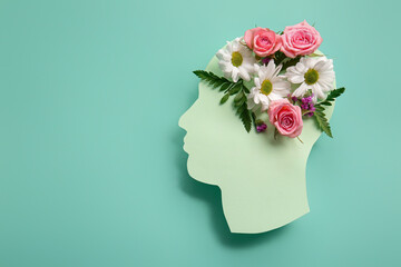Paper human head with flowers on turquoise background. World Mental Health Day
