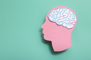 Paper human head with brain on turquoise background. World Mental Health Day
