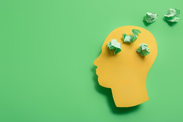Paper human head with crumpled paper on green background. World Mental Health Day