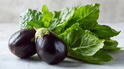 Obraz premium Fresh Eggplants and Green Leaves on a Textured Surface.