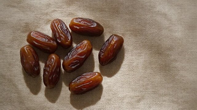 Overhead shot of sweet dried dates on beige linen fabric. Natural, organic, and healthy Mediterranean snack.