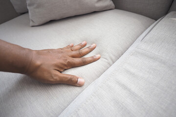 Hand touching soft couch fabric in living room space