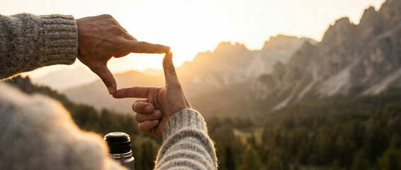 Hands framing mountain scenery at sunset for creative photography expression