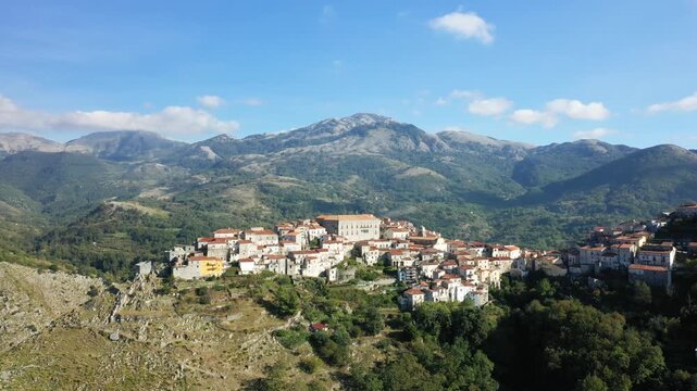 Scenic aerial view of the historic village of Aieta nestled among lush green mountains under a clear blue sky. Picturesque landscape with traditional architecture and natural surroundings.