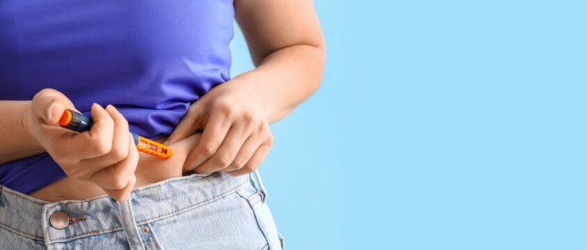 Woman with diabetes giving herself injection of insulin on light blue background with space for text, closeup
