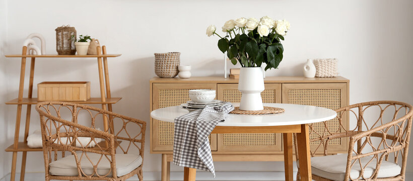 Interior of light room with white roses in vase on dining table