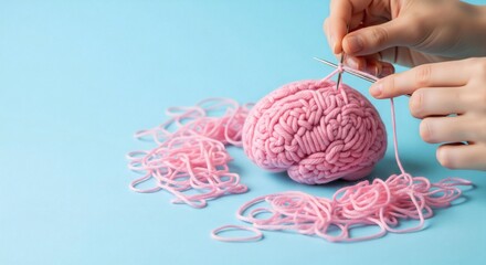 Human brain made of pink yarn being knitted with metal needles by hands on a blue background. Conceptual studio photography. Creativity, learning process and mental health concept 