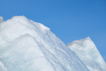 Ice pyramids on blue sky background.