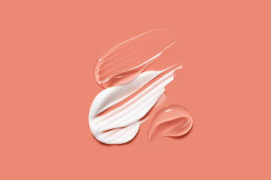 Cosmetic cream gel smears. White skin care product creamy texture. Serum, lotion swatch on coral background
