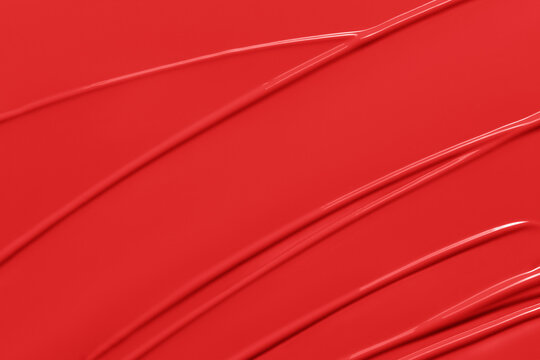 Red lipstick texture background.  Creamy lip makeup product or paint swatch. Lliquid lipstick or lip gloss smear closeup