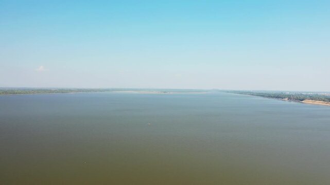 Aerial view of the expansive West Baray reservoir with calm water and distant shoreline under a clear blue sky in Cambodia.