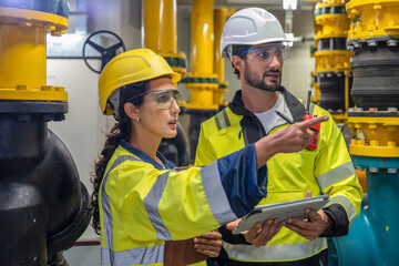 Focused engineering team reviewing HVAC blueprints in a professional industrial setting.