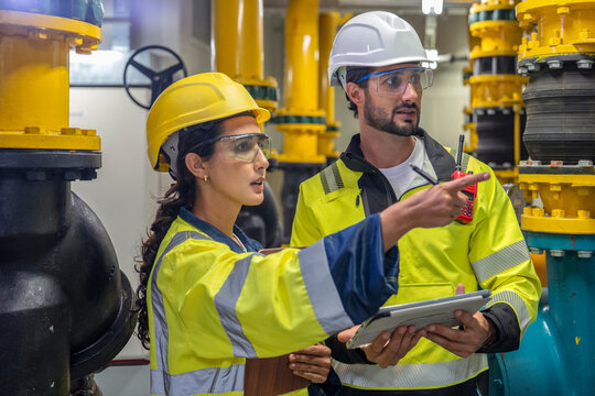 Focused engineering team reviewing HVAC blueprints in a professional industrial setting.