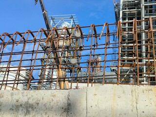 Construction worker tying deformed steel reinforcement bars with concrete cover blocks.