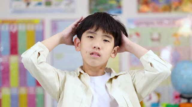 Stressed Asian Schoolboy Holding His Head in a Classroom Setting