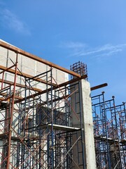 Reinforced concrete column with exposed rebar and scaffolding at a construction site