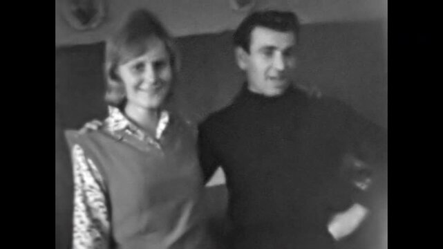 Old film, young couple smiling during home party, gathering in 1970s. Charm man embraces woman affectionately. Male flirtation in romantic relationships. Old film. Archival retro. Vintage archive