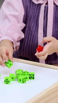 Child's Hands Playing with Green Math Manipulative Cubes on White Board