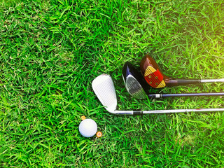 Golf clubs and golf balls on a green lawn in a beautiful golf course