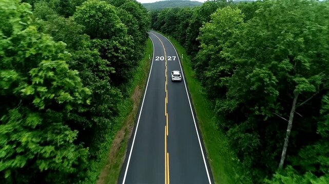 Winding forest road marked with future years symbolizing progress and the passage of time. Aerial drone view of cars driving towards the future, representing growth, opportunity, and journey ahead.