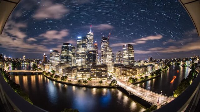 Cityscape at night, with river reflections and light trails