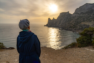 Woman sunset sea watching dramatic golden ocean view from rocky cliff edge © svetograph