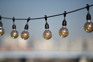 Obraz premium Hanging light bulbs against a blurred cityscape