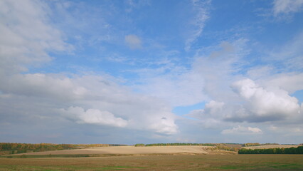 Fototapeta premium A beautiful and scenic landscape featuring an expansive cloudy sky over open fields and hills