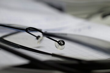 Close-up of eyeglasses resting on sheet of graph paper with faint handwritten notes in blurred background. Perfect for education, study, vision, academic, analytical