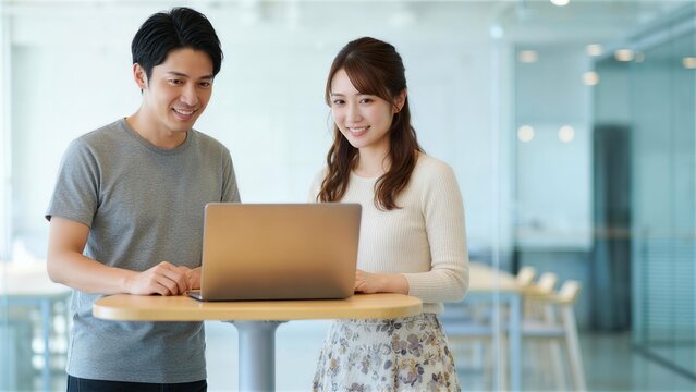 ハイテーブルでパソコン画面を確認するカジュアルな男女
