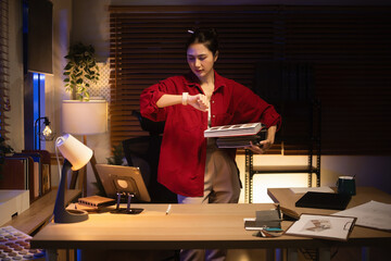 Late night interior designer reviewing catalogs and checking time, showing dedication and overtime work at home