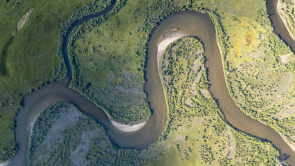 Aerial view of meandering river surrounded by lush green vegetation River in valley with forest and mountain backdrop © Михаил Уванов