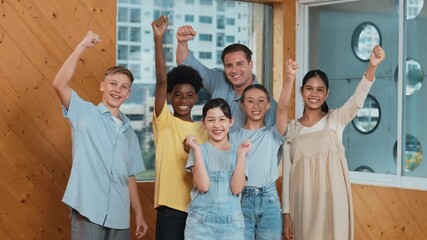 Smart teacher and diverse student standing while putting hand in the air to celebrate successful project.. Skilled instructor with high school children with mixed races in casual outfit . Edification
